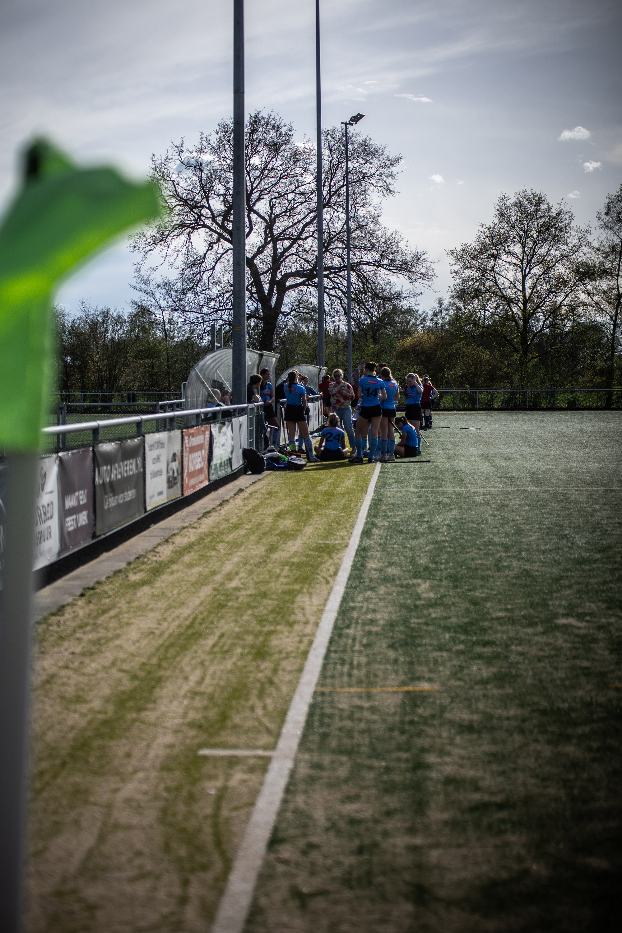 A group of people play hockey on a field, sponsored by Smhc.