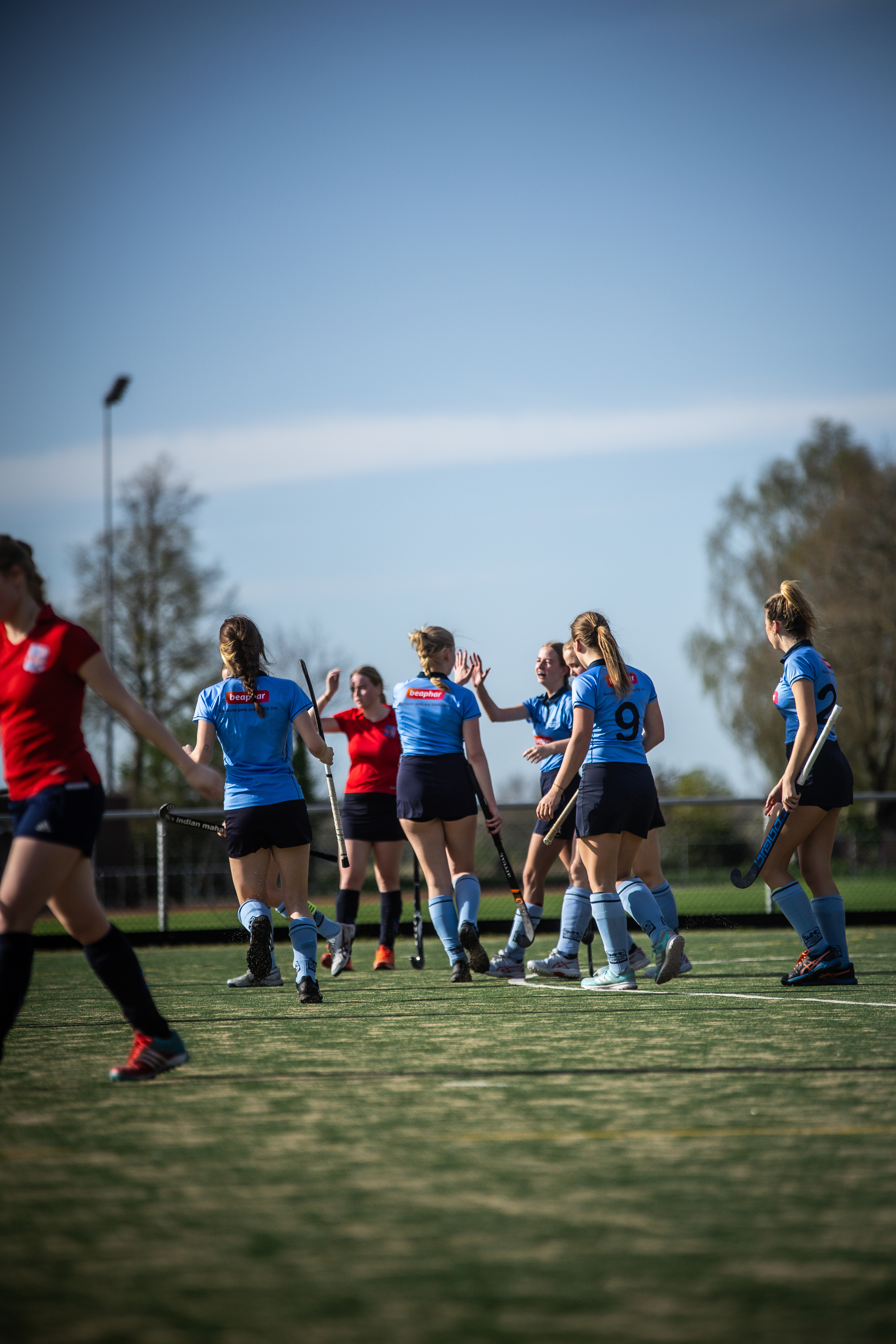 A group of women in blue hockey uniforms standing on a field.