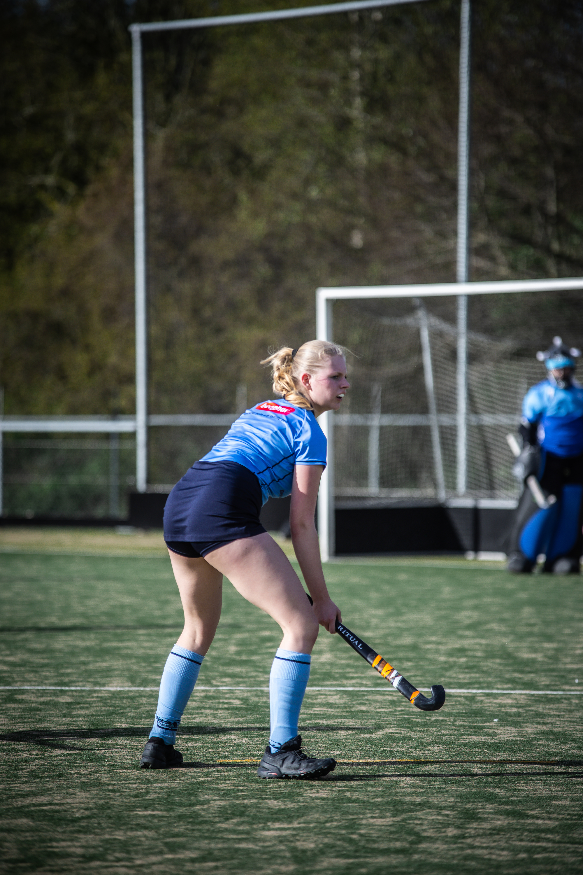 A hockey player with the number 3 on her back is about to strike the ball.