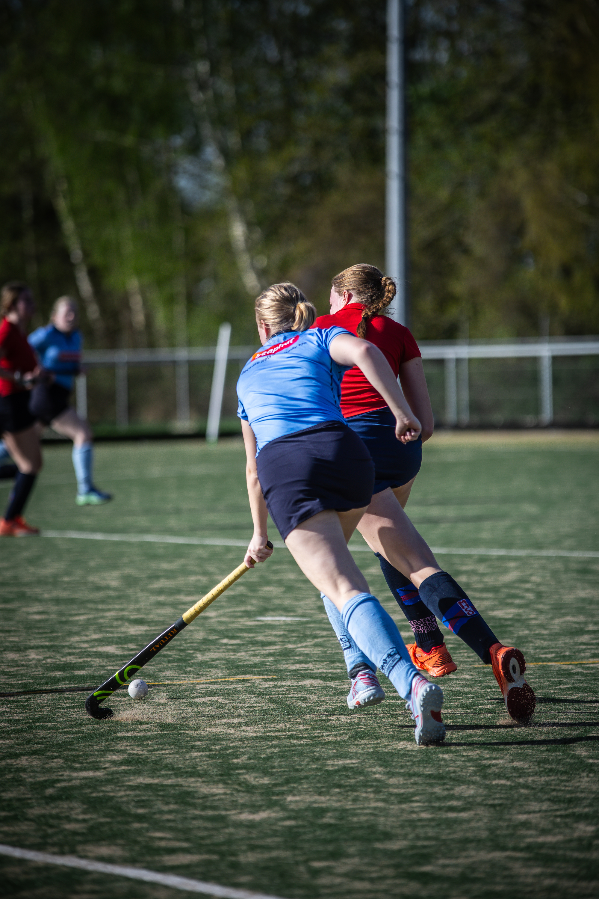 A group of hockey players on a field in blue jerseys.