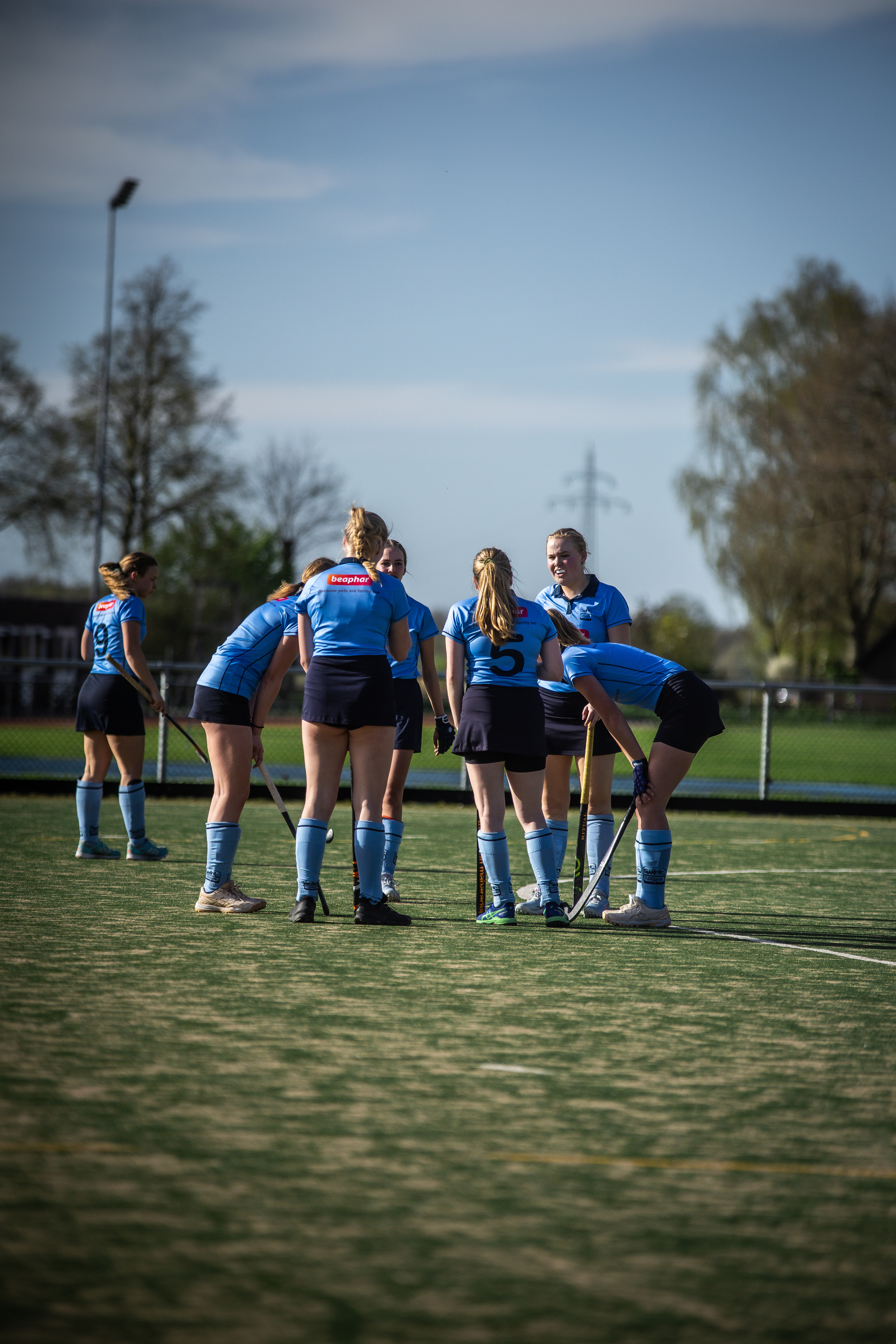 Hockey players on the court, one with their stick down and others standing next to each other.