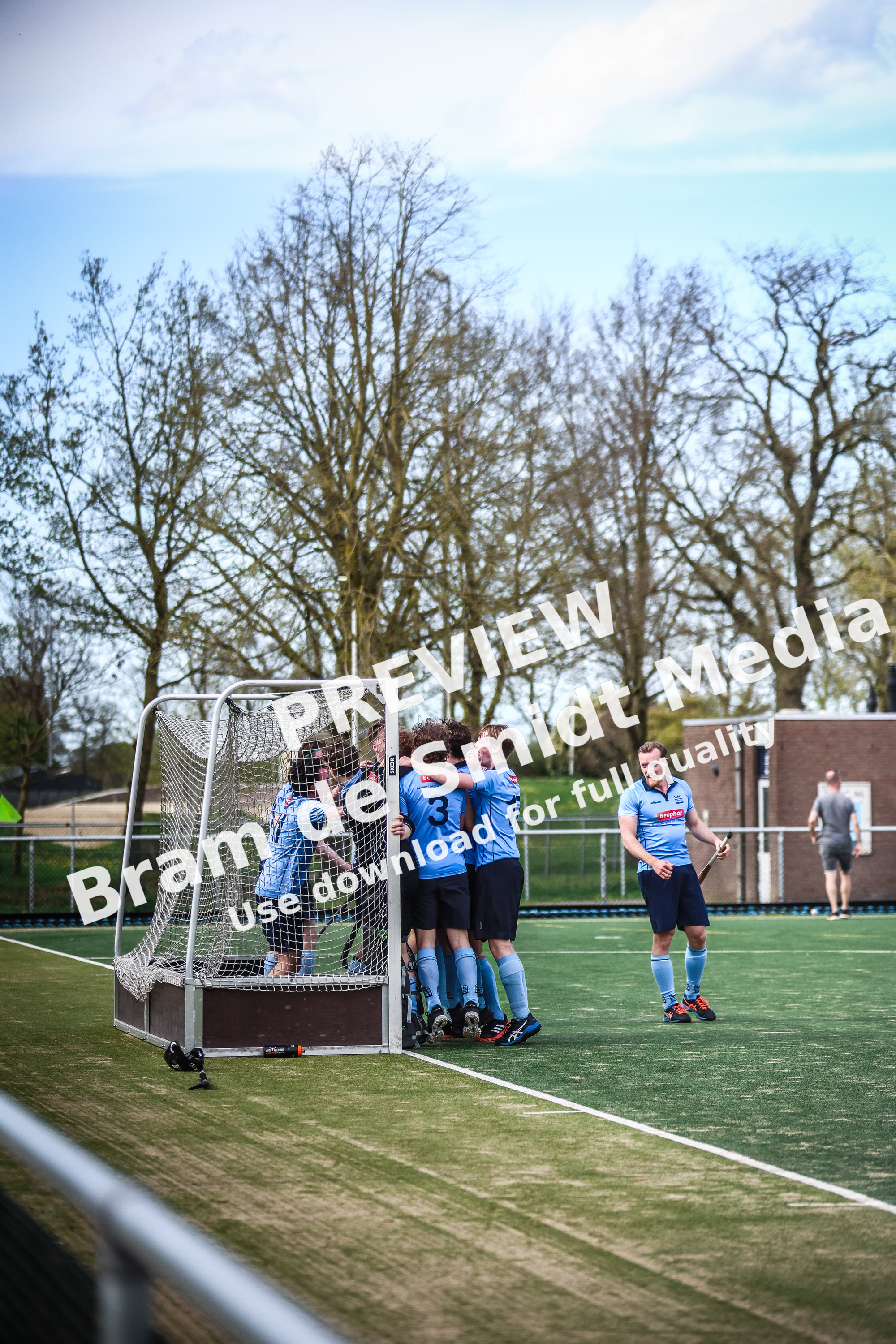 Hockey players celebrate with a teammate on the field.