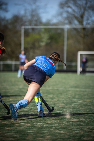 Young athlete playing hockey on the field in blue uniform.