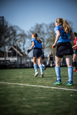 Two girls playing a game of hockey on a field in the year 2024.