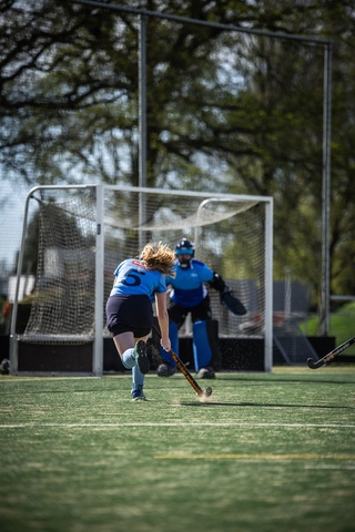 A hockey game on a field with blue and black uniforms.