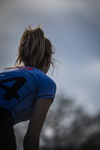 A girl wearing a blue shirt with the number 4 on the back.