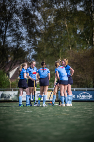 A group of women wearing blue hockey uniforms stand on a field.