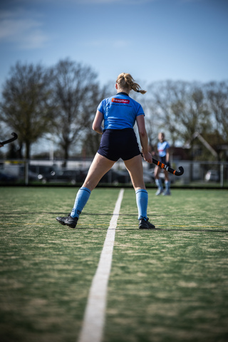 A woman playing hockey, wearing a blue jersey that says "SMHC" on the back.