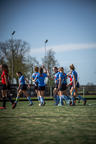 Hockey players on a field wearing blue uniforms in front of the crowd.