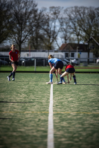 A group of girls playing hockey, one of them is wearing a number 14.