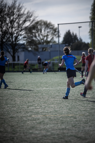 a woman in a blue jersey and black shorts playing soccer with other people on the field.