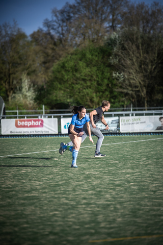 Two female athletes run on a field with an advertisement for Peakhar.