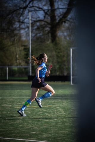 A young girl is playing soccer and is running across a field.