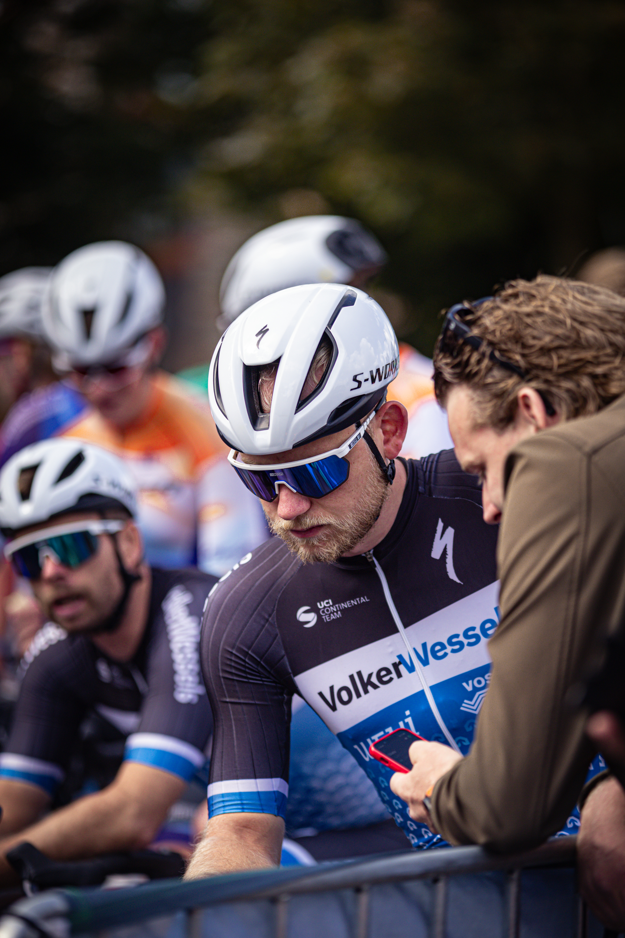 A man at a bike race wearing a helmet with the number 1 on it and looking down.