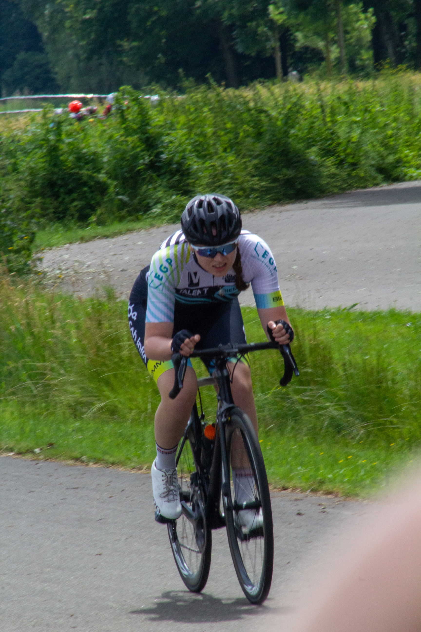 A person is riding a bike in a grassy area, wearing a helmet and glasses.