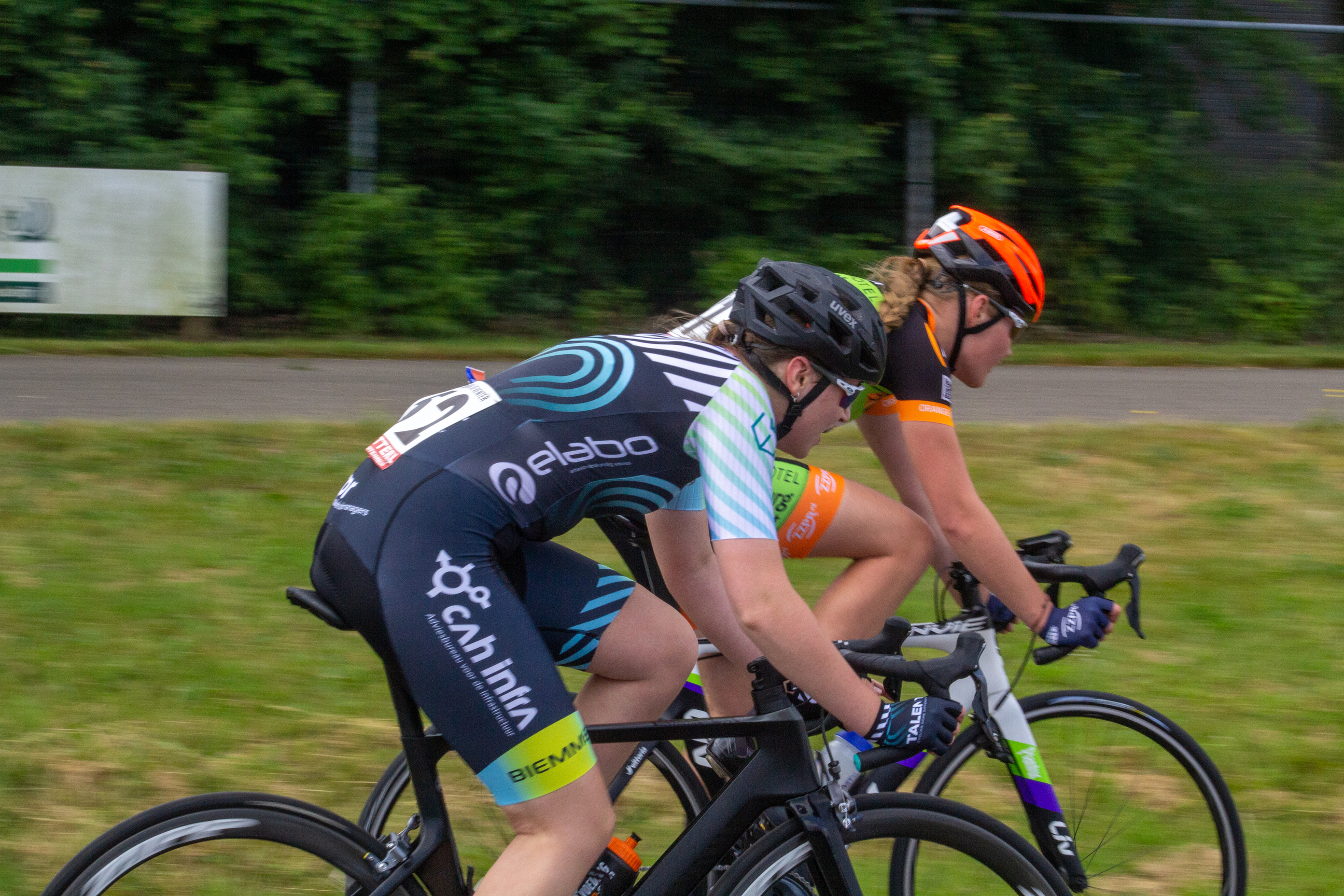 Two women are on their bikes, racing in a race sponsored by Giant.