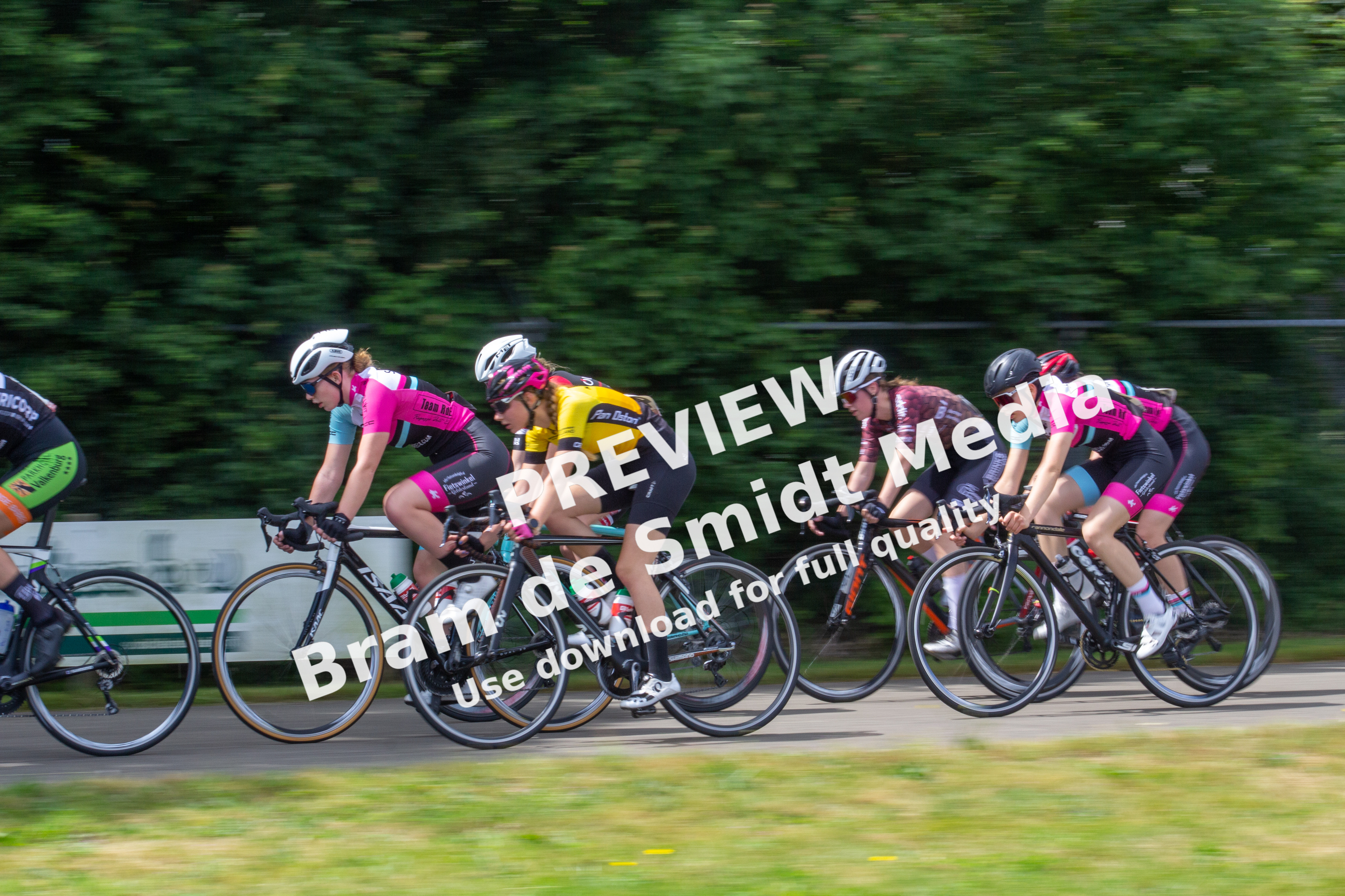 Dame ronde van Deventer, 2021: Six women in black and pink racing bikes, riding on a road next to trees.