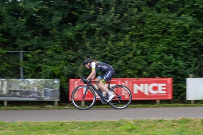 A person is riding a bike in front of a sign with the word NICE on it.