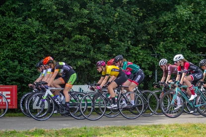 A group of women are riding bicycles in a race, each wearing a different jersey.