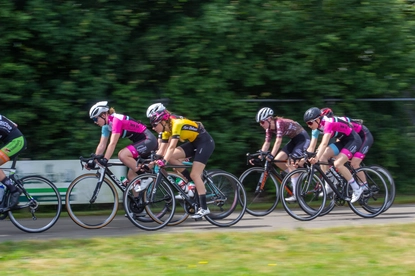 Dame ronde van Deventer, 2021: Six women in black and pink racing bikes, riding on a road next to trees.