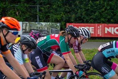 Several cyclists are part of a race, and the background features an advertisement for Wielrennen.