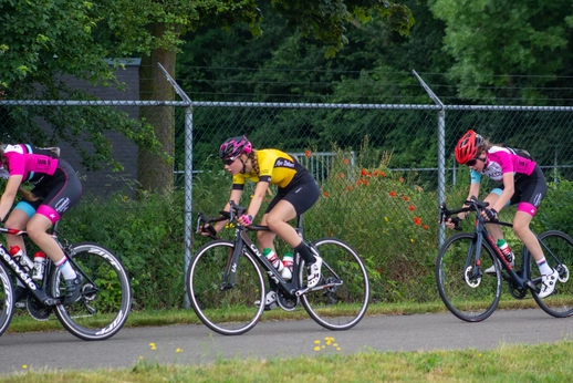 Women in a bike race. The woman on the right is wearing a red helmet.