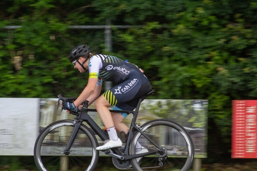 A cyclist in a green and blue jersey is riding a bike.