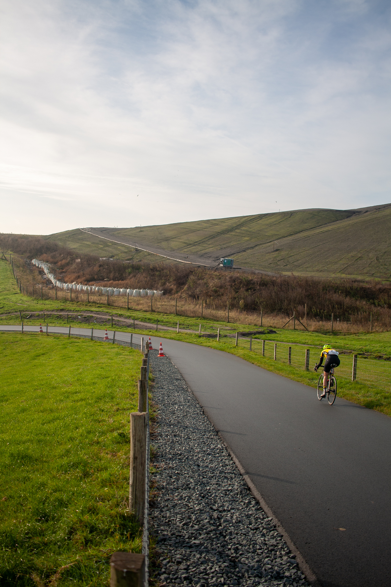 A person riding a bicycle on a paved road in a rural area.