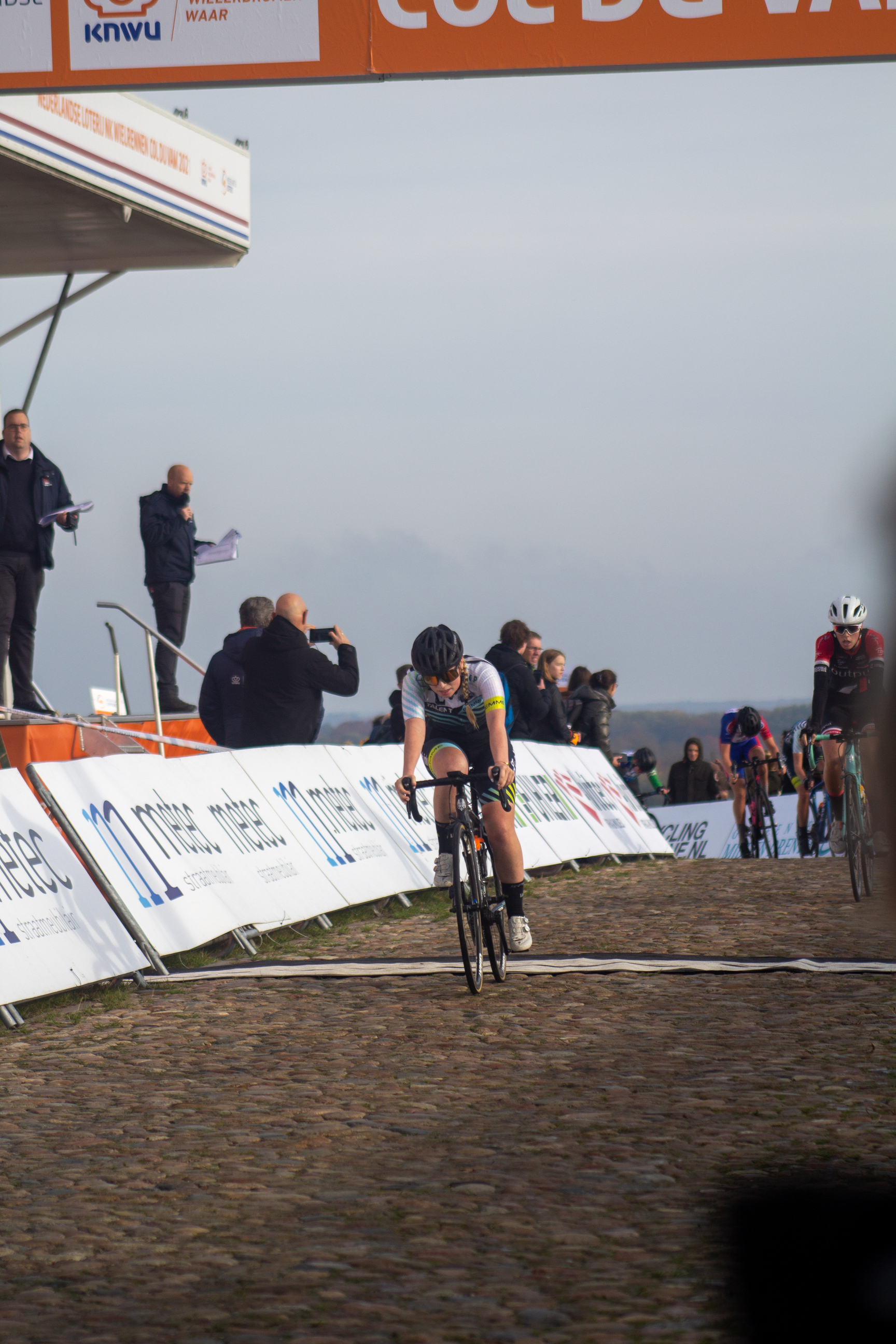 A cyclist races down a cobblestone street during the NK Nieuweling Dames race.