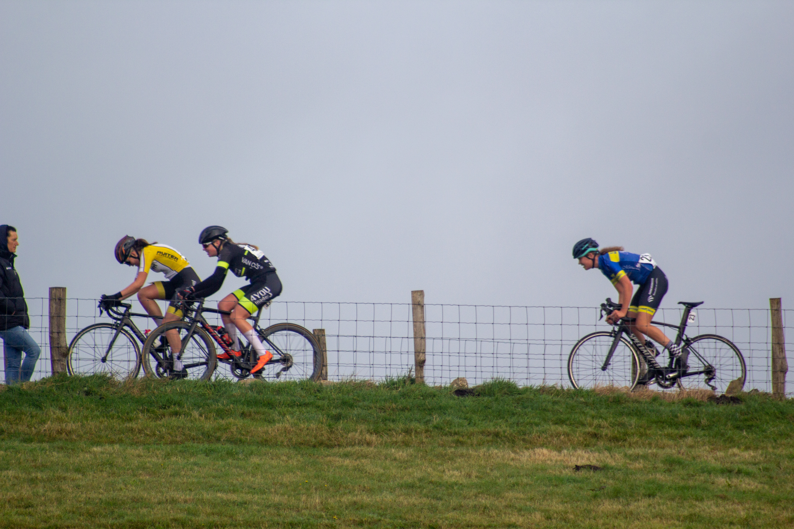 A group of cyclists racing on a grassy hill in 2021.