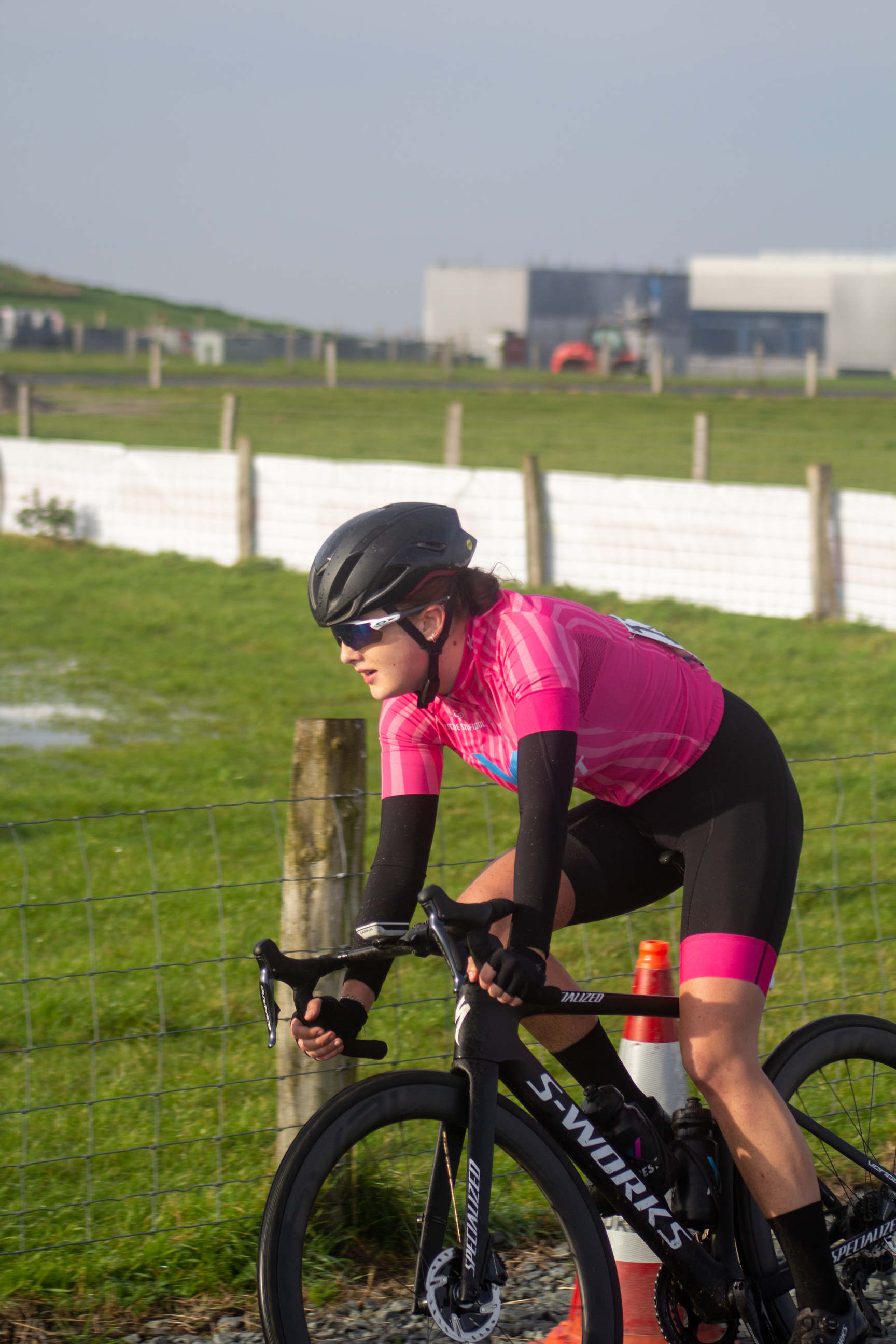 A woman wearing a pink shirt and helmet riding a bike.