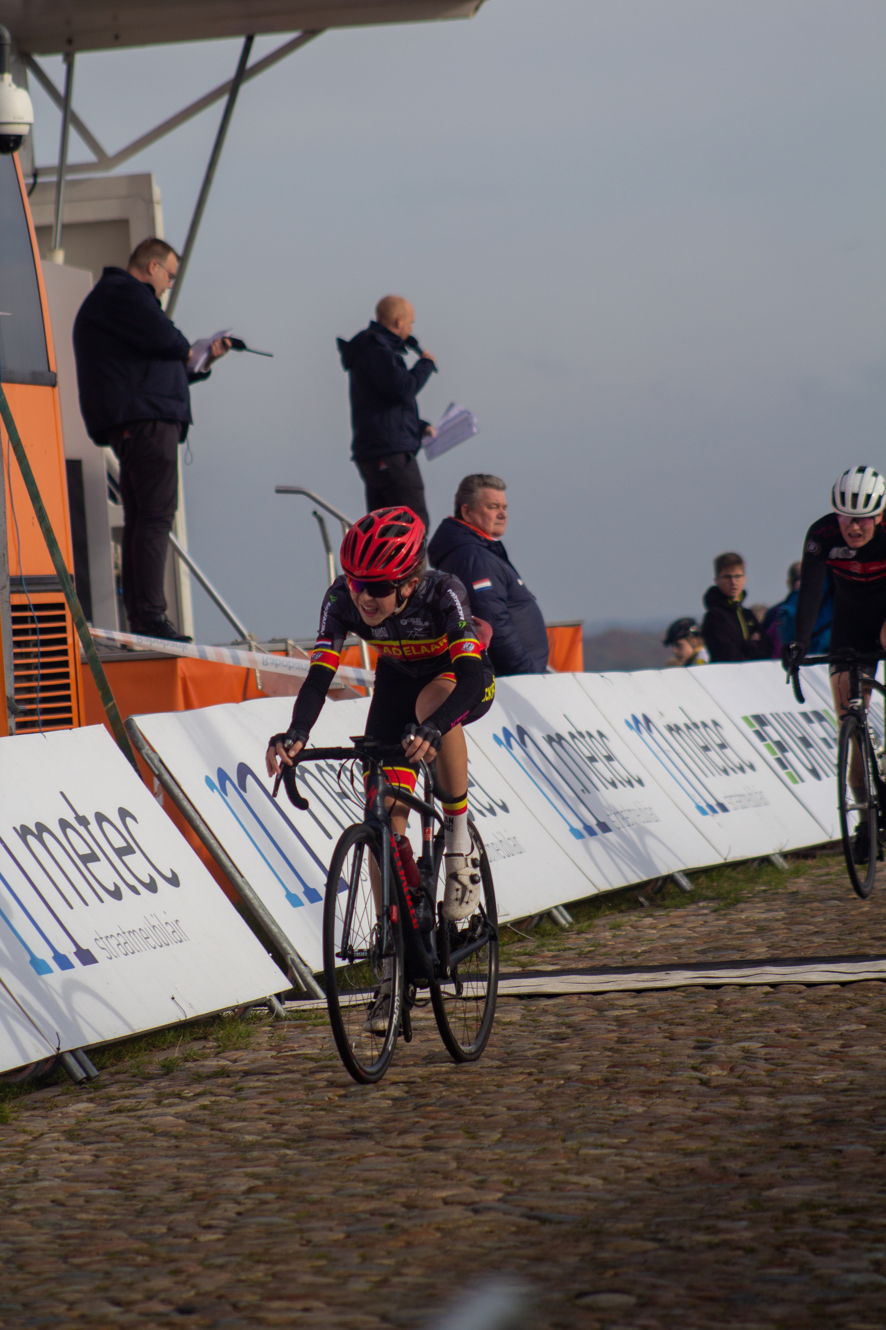 Two cyclists racing on cobblestones at the NK Nieuweling Dames race.