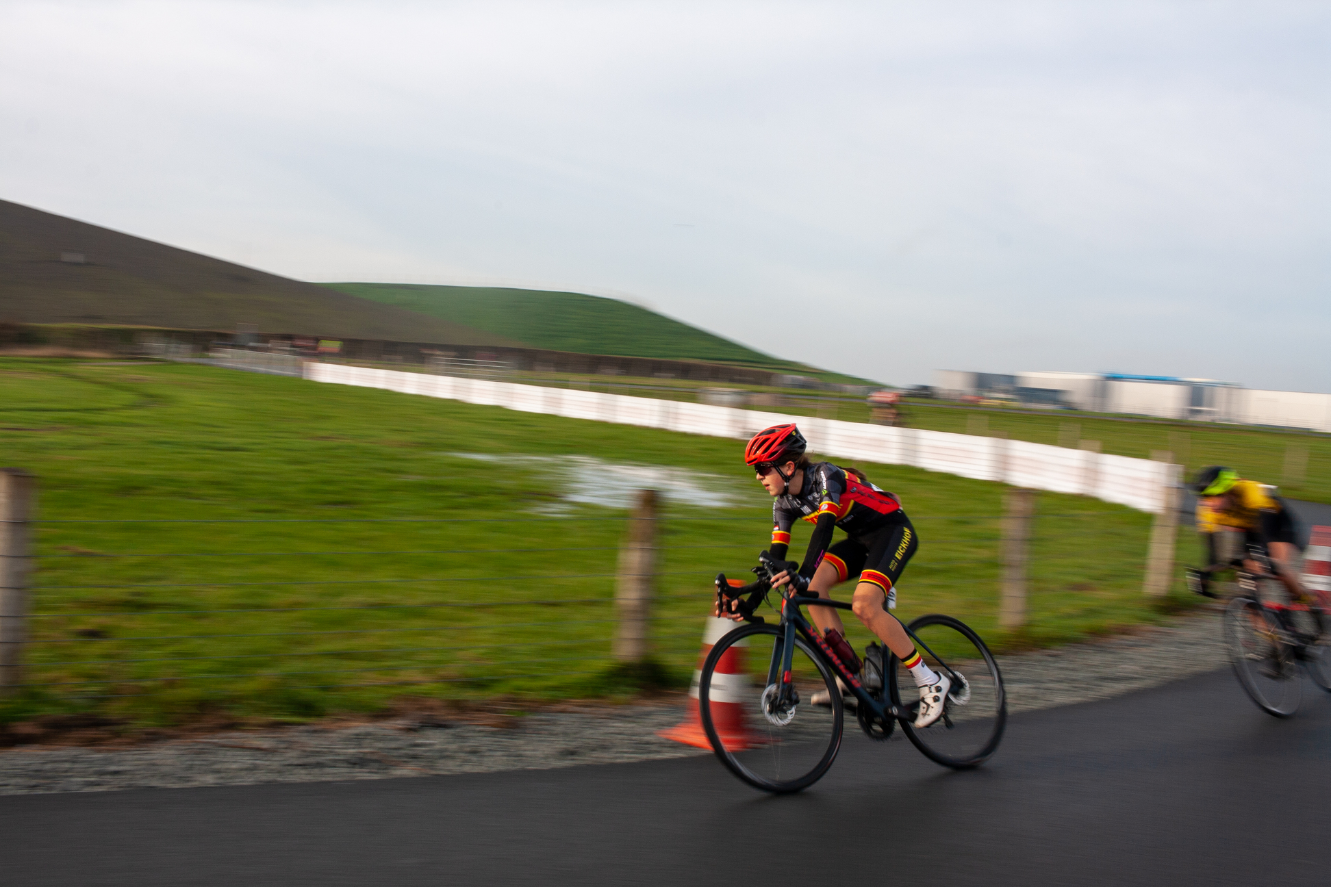 A cyclist on a mountain bike is wearing red helmet and racing down the road.