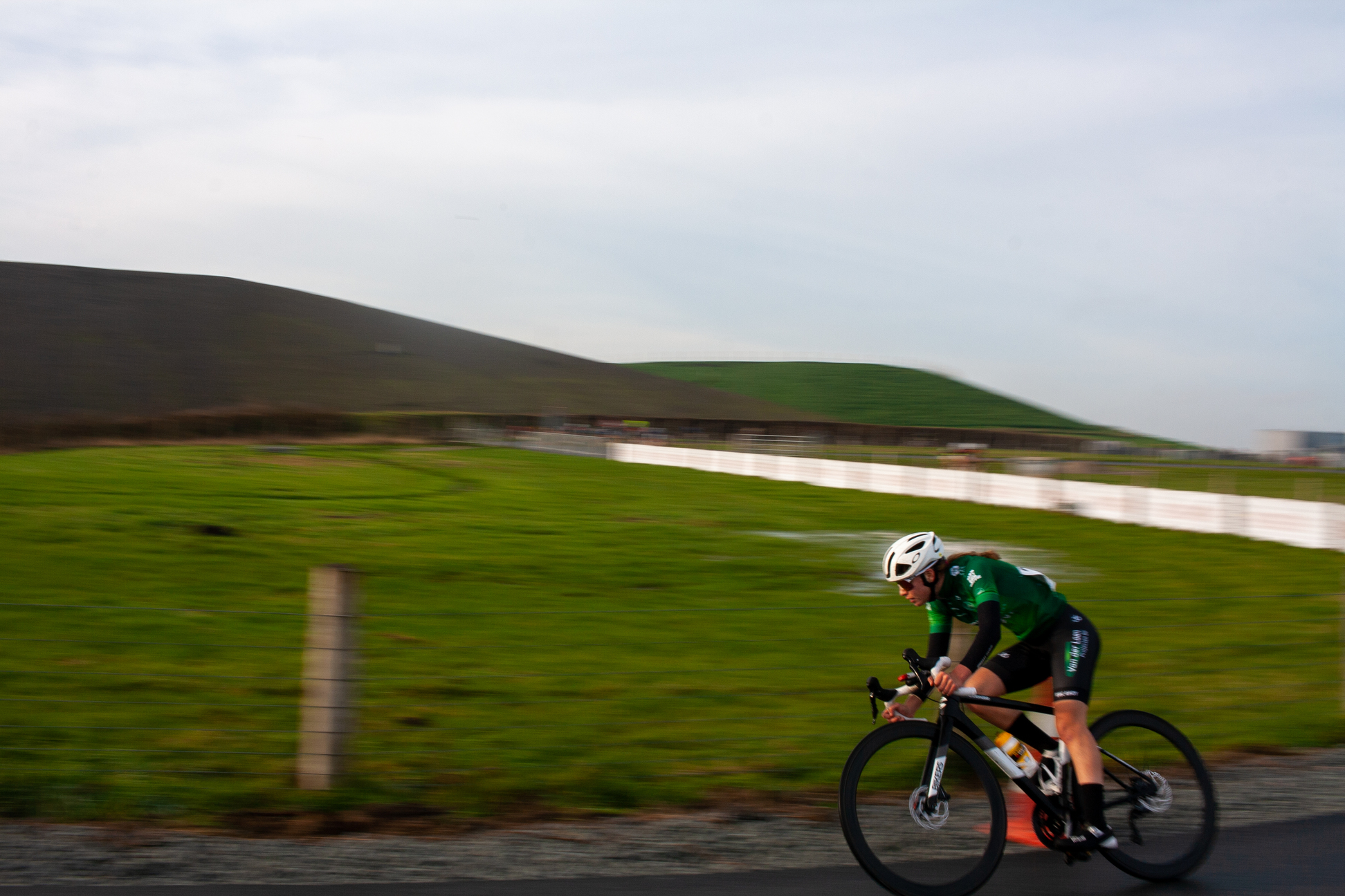 A man in a green jersey is riding a bicycle on a road.