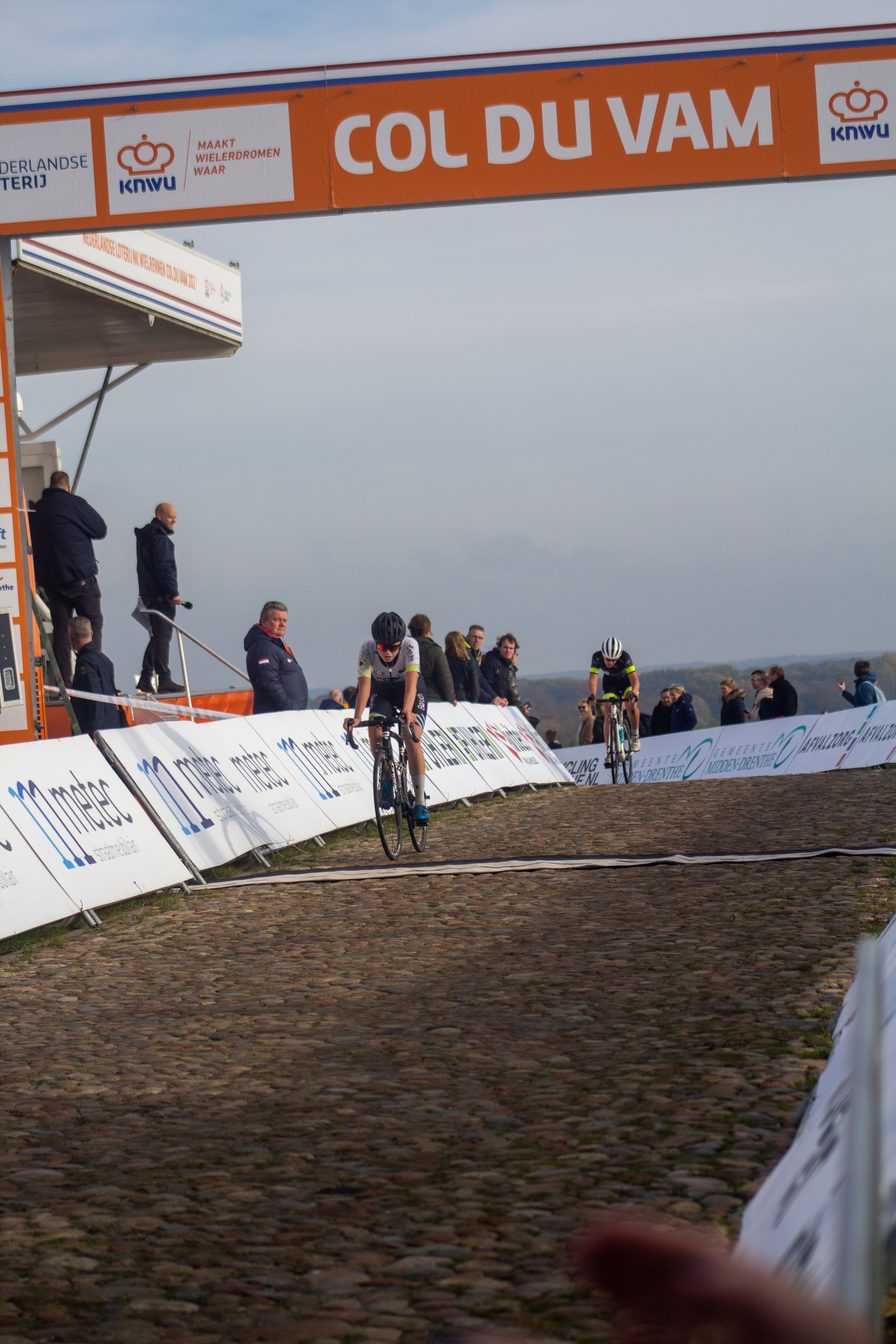 A group of cyclists are riding down a track in front of a crowd.