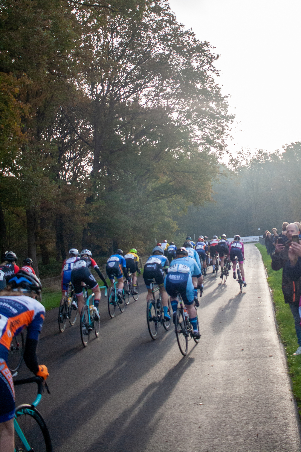 A group of people race on a road near a grassy area.