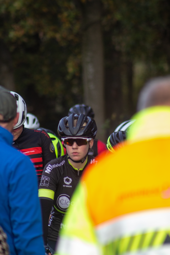 A group of cyclists in a race, the central rider has an orange reflector on their back.