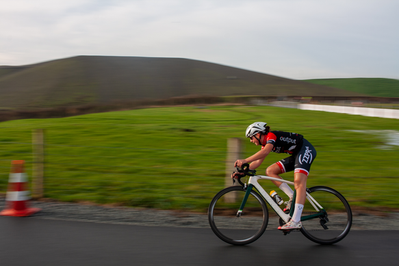 A person in a red, white and black outfit riding a bicycle down the road.