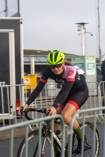 Woman riding a bike while wearing a helmet and cycling gear.