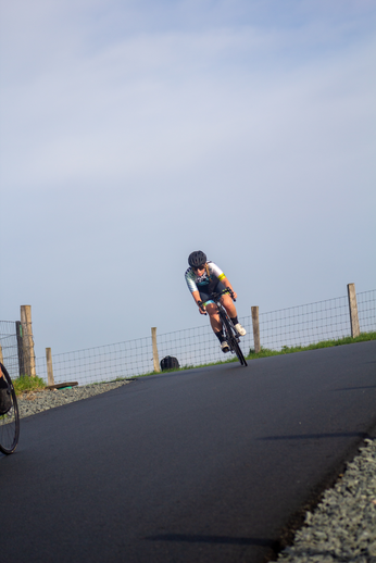 A female cyclist is in motion on a paved road during NK Nieuweling Dames.