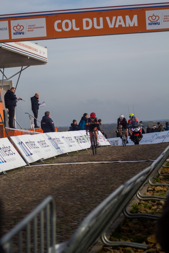 Two bicyclists race down a track in front of a crowd watching the event.