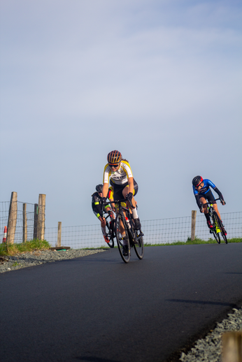 Three cyclists on a road, one in the lead and two behind.