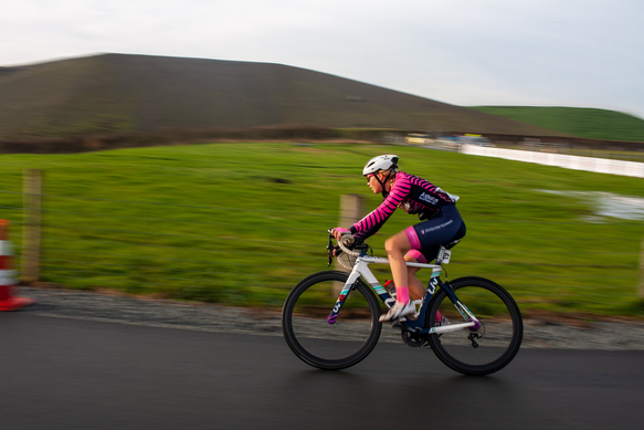 A person wearing a pink top and white helmet riding a bike down the road.