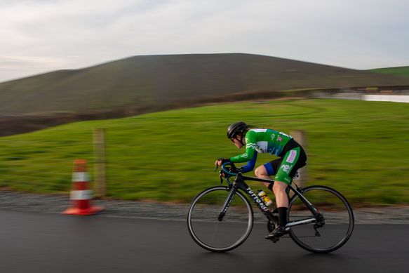 A cyclist riding on a road with a cone placed next to the path.