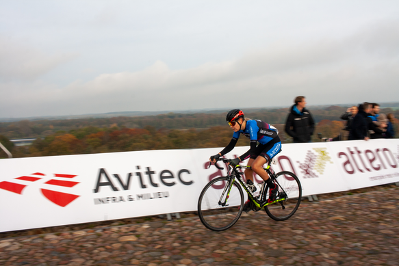 A cyclist riding down the road, with people looking on from the side of the track.