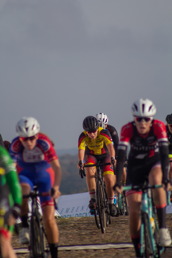 Group of cyclists wearing helmets racing on a cobblestone road.