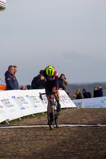 A cyclist wearing number 4 is riding a bike in front of an audience.