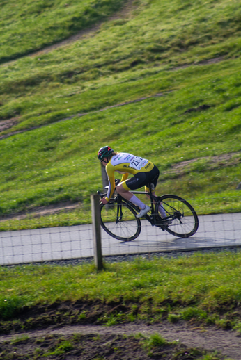 A cyclist is wearing a yellow and white shirt with the number 20 on it.