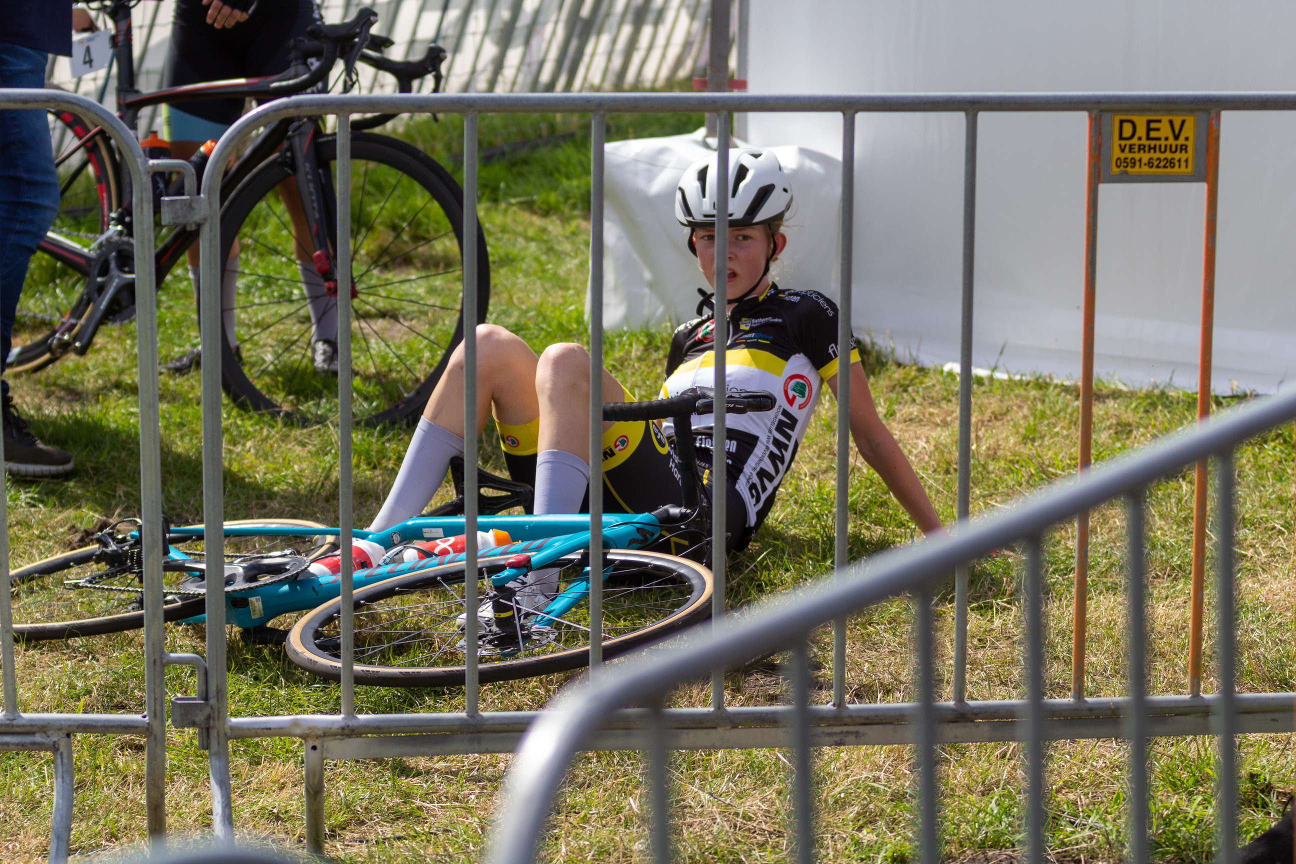 A young woman has a bicycle in front of her. She is wearing a jersey with the number 7 on it and a white helmet.