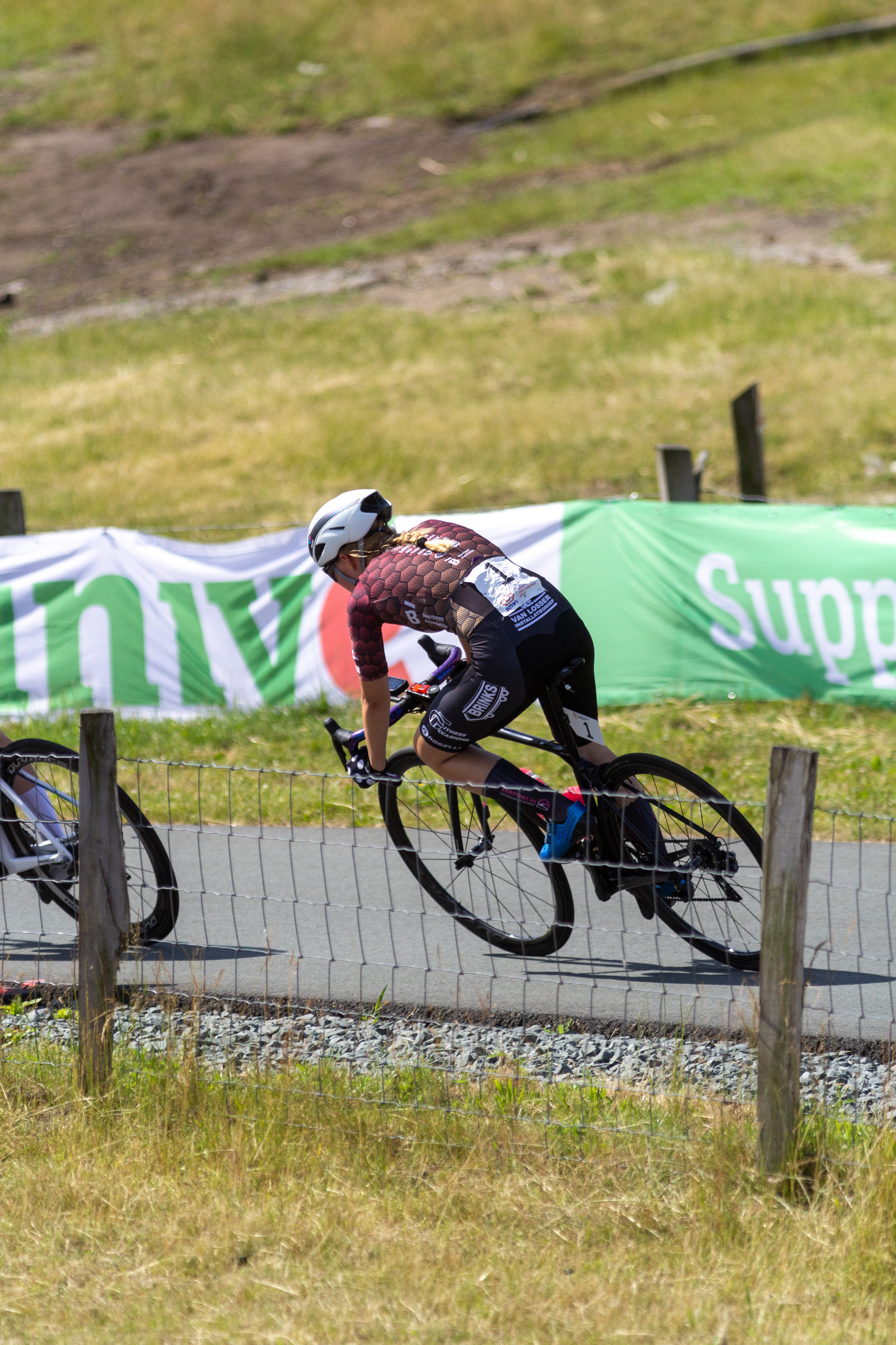 A person in a purple and black shirt is racing on a bike.